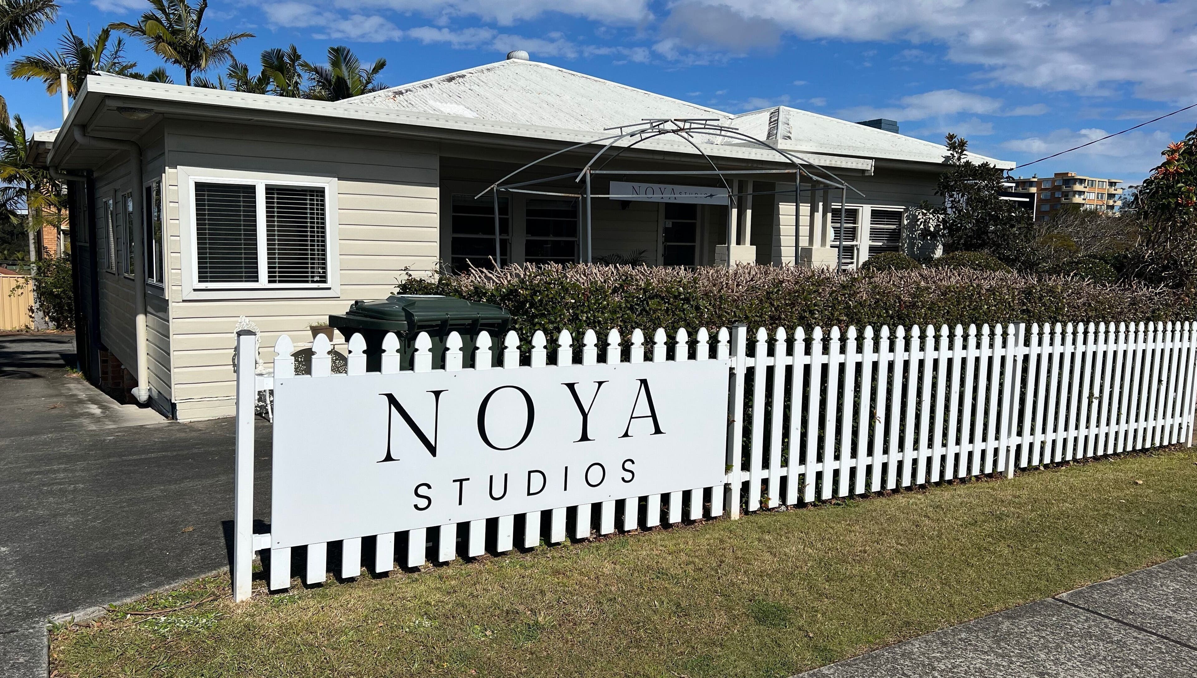NOYA Studios exterior in Port Macquarie, New South Wales, AU showcases charming white fence and lush greenery.