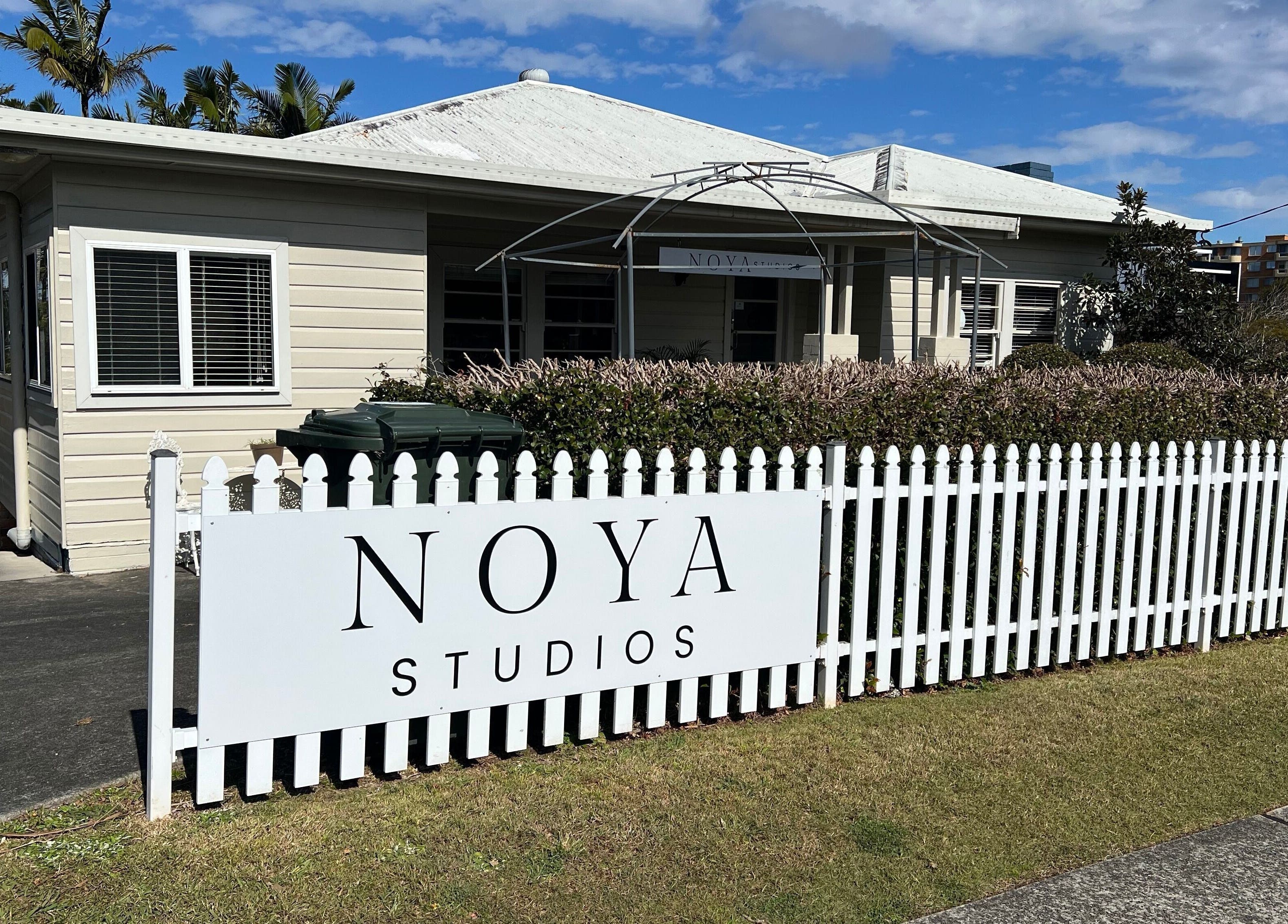 NOYA Studios exterior in Port Macquarie, New South Wales, AU showcases charming white fence and lush greenery.