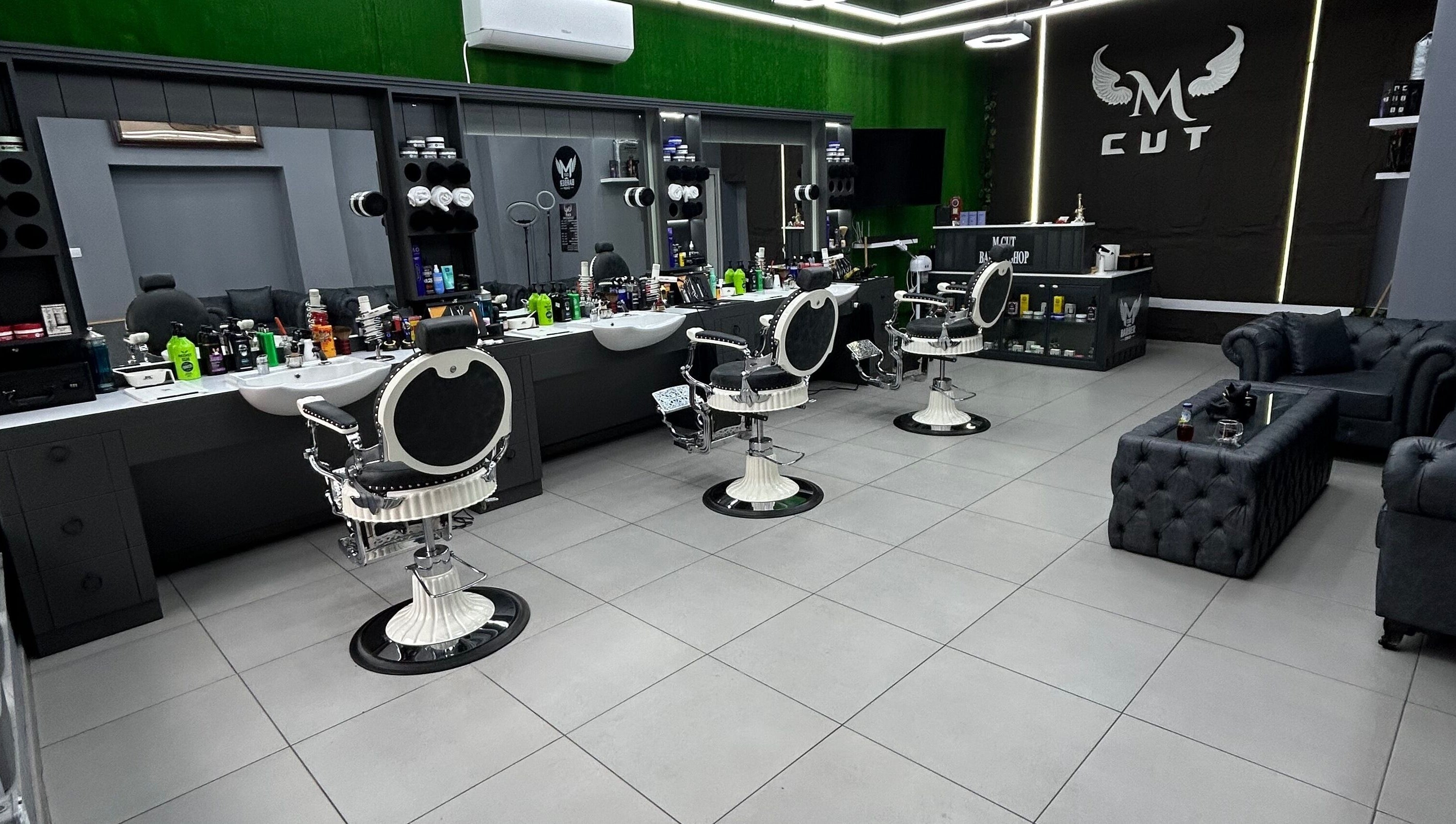 Интериор на салона M.cut в Ямбол, Ямбол, BG, с модерни бели бръснарски столове и елегантен декор.