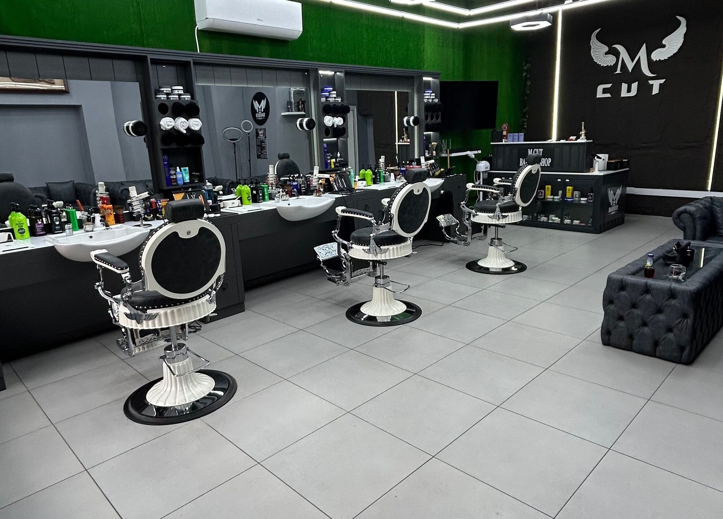 Интериор на салона M.cut в Ямбол, Ямбол, BG, с модерни бели бръснарски столове и елегантен декор.