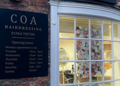 Coa Hair exterior in York, England with a sign displaying opening times and floral window decor.