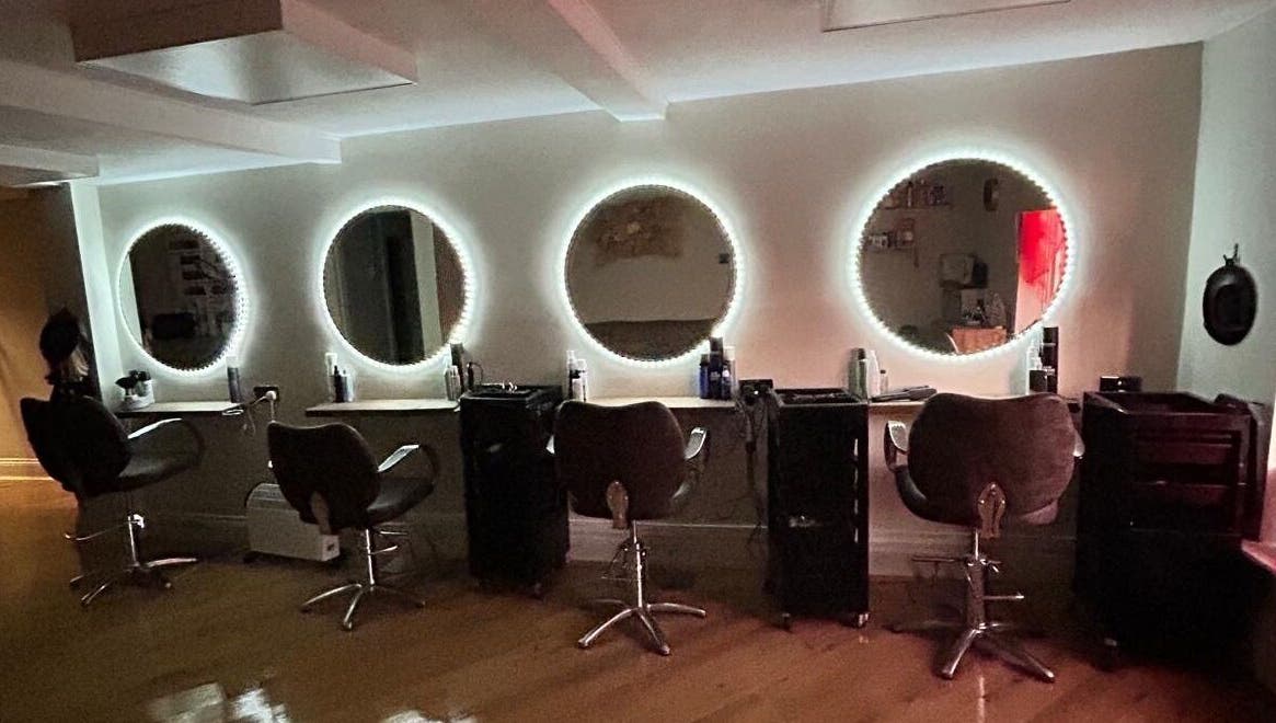 Coa Hair salon in York, England, GB features chic styling chairs with illuminated round mirrors.