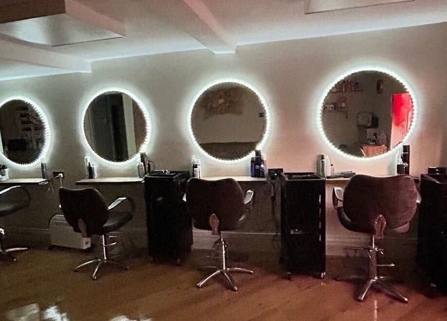 Coa Hair salon in York, England, GB features chic styling chairs with illuminated round mirrors.