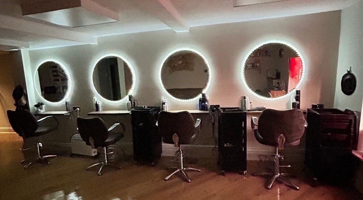 Coa Hair salon in York, England, GB features chic styling chairs with illuminated round mirrors.