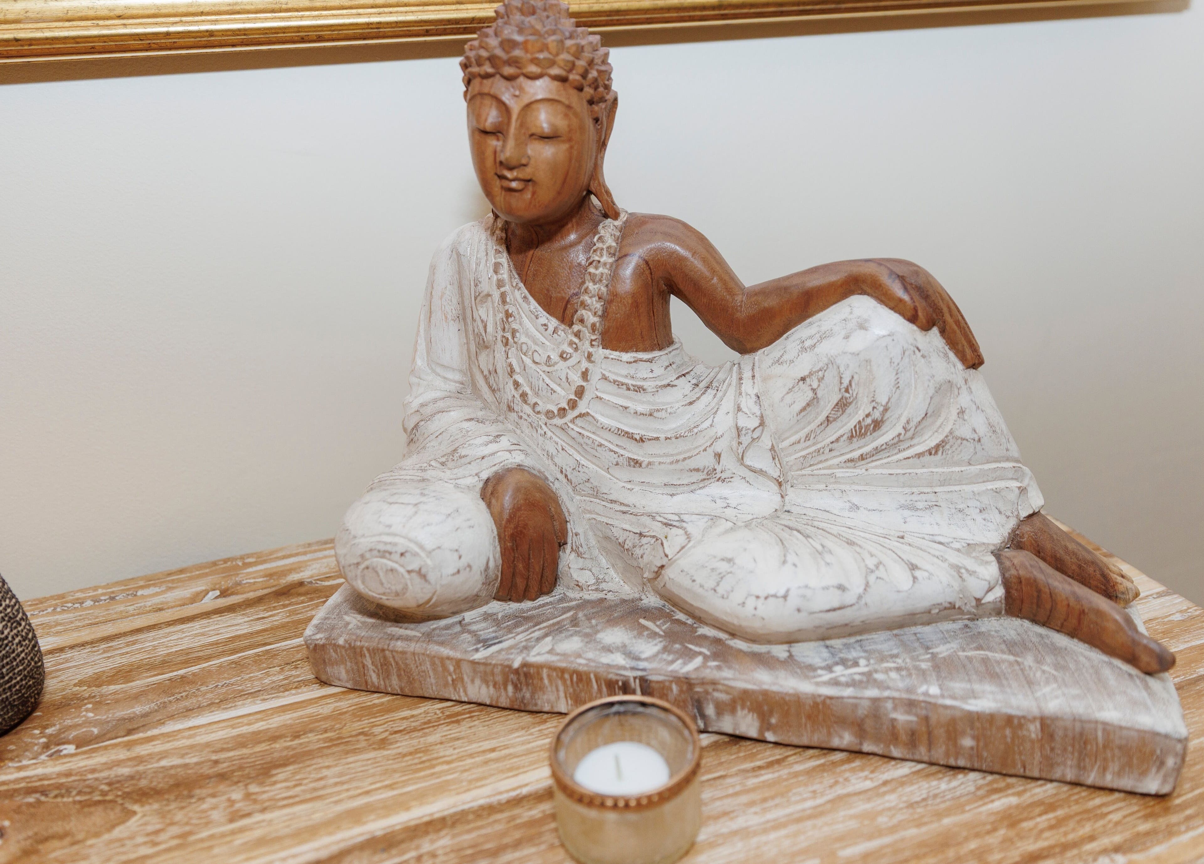 Wooden Buddha statue and candle at Taksu SPA, București, București, RO, promoting tranquility and relaxation.
