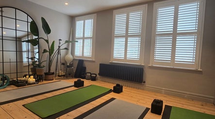 Peaceful yoga studio at GiYAS Therapy, London, England, GB with mats, mirrors, and plants.