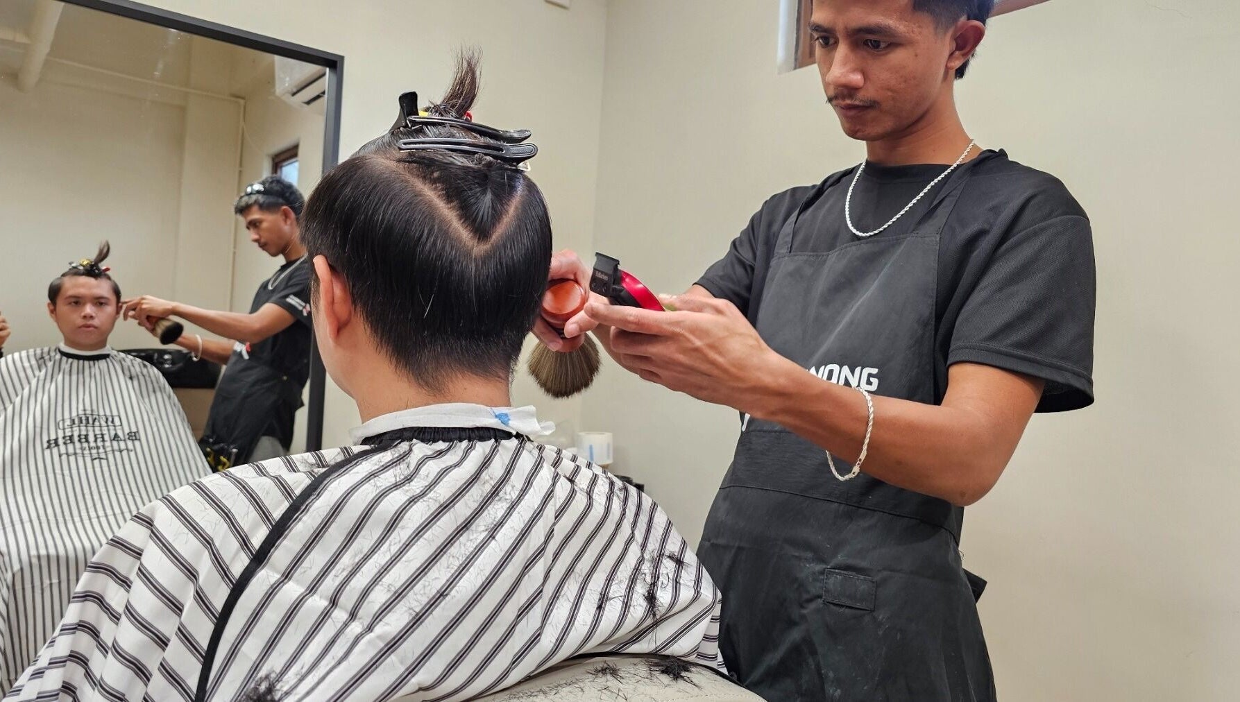 Barber providing a haircut at Manong Barbers Katipunan, QC, located in Quezon City, Metro Manila, PH.