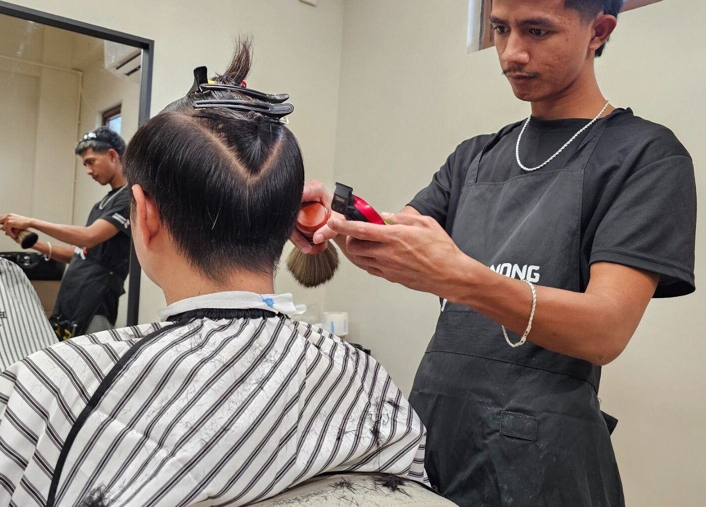 Barber providing a haircut at Manong Barbers Katipunan, QC, located in Quezon City, Metro Manila, PH.