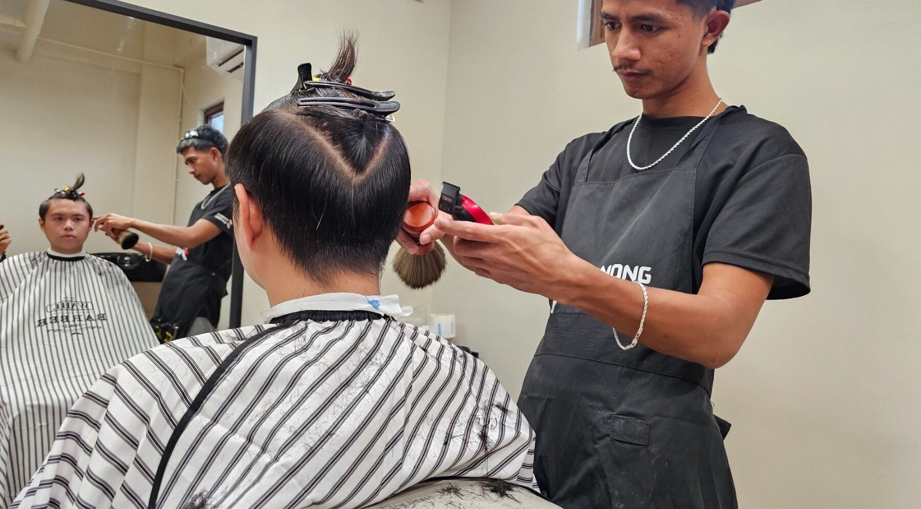 Barber providing a haircut at Manong Barbers Katipunan, QC, located in Quezon City, Metro Manila, PH.
