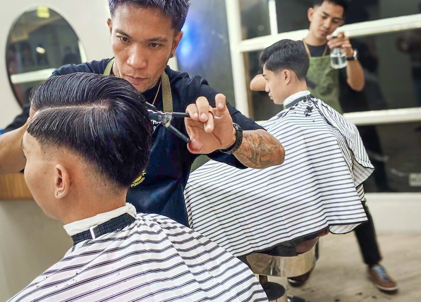 Barber crafting a sharp haircut at Manong Barbers Katipunan, QC, Quezon City, Metro Manila, PH.