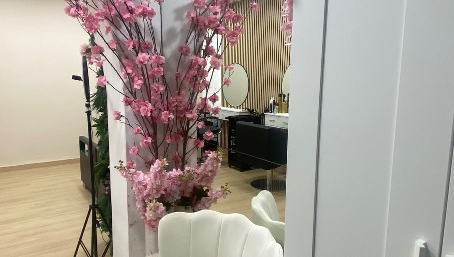 Interior do Aura Salon em Aveiro, Aveiro, PT, decorado com flores rosas e cadeiras elegantes.
