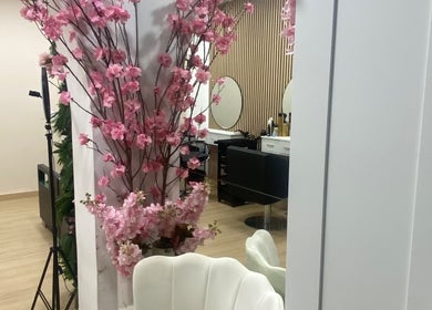 Interior do Aura Salon em Aveiro, Aveiro, PT, decorado com flores rosas e cadeiras elegantes.