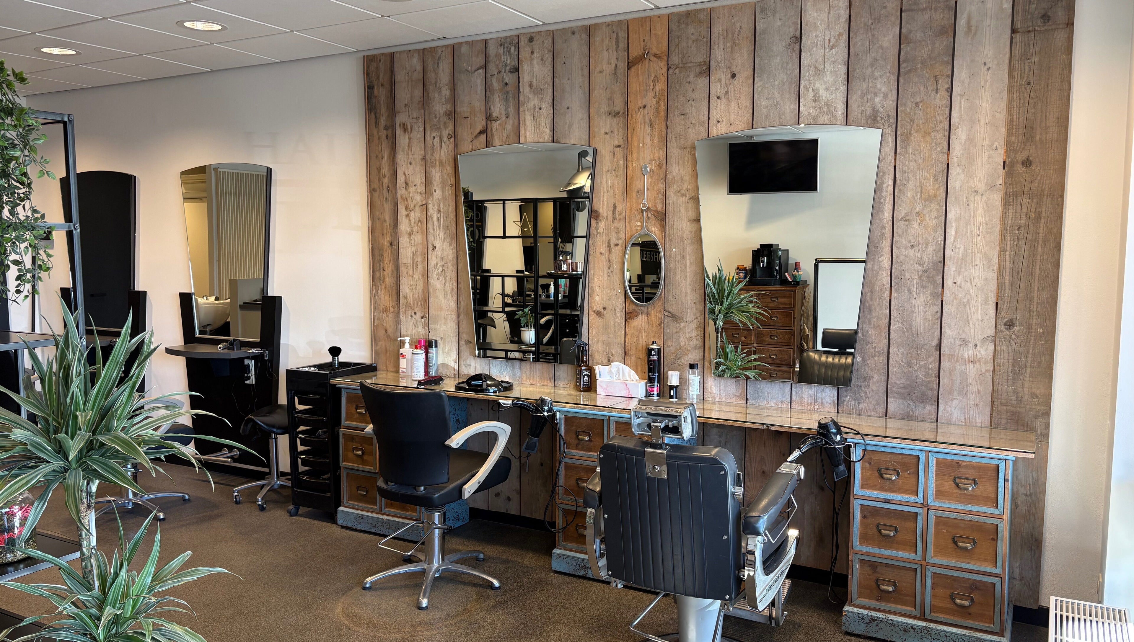 Modern interieur bij HAIRSTUDIO REESHOF, Tilburg, Noord-brabant, NL met houten wand en kappersstoelen.