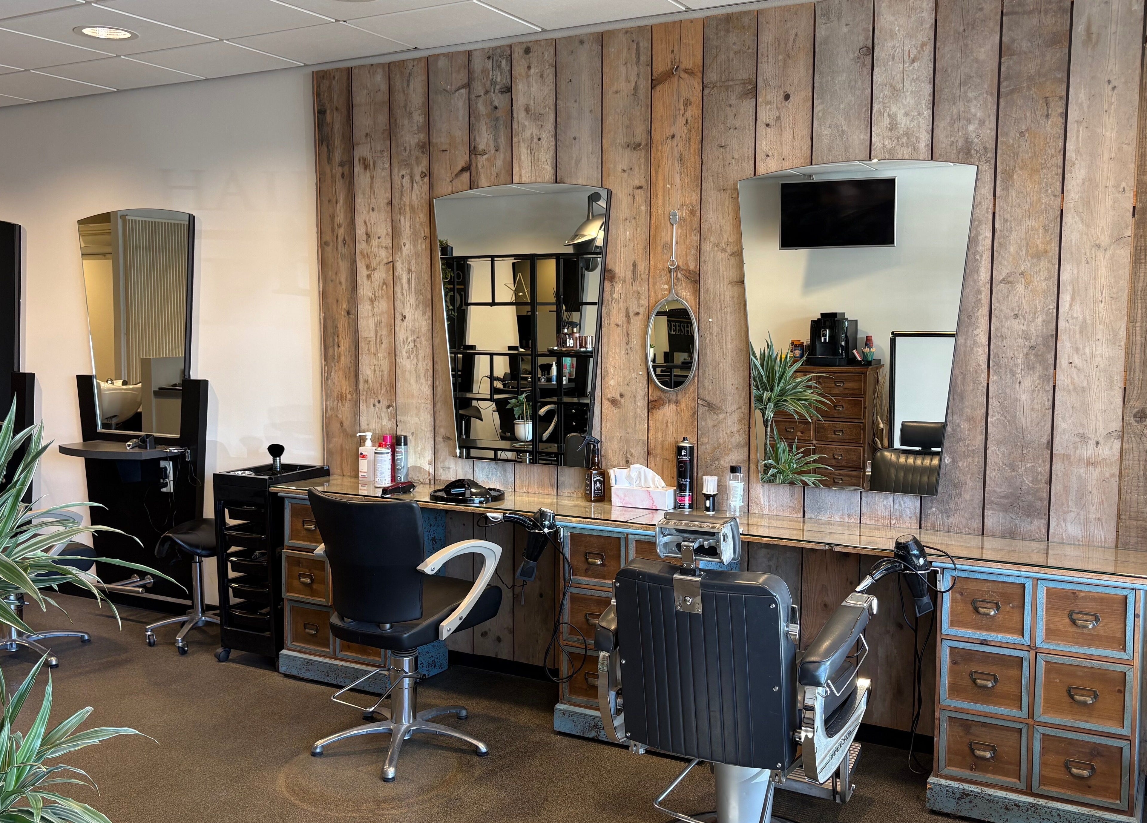 Modern interieur bij HAIRSTUDIO REESHOF, Tilburg, Noord-brabant, NL met houten wand en kappersstoelen.