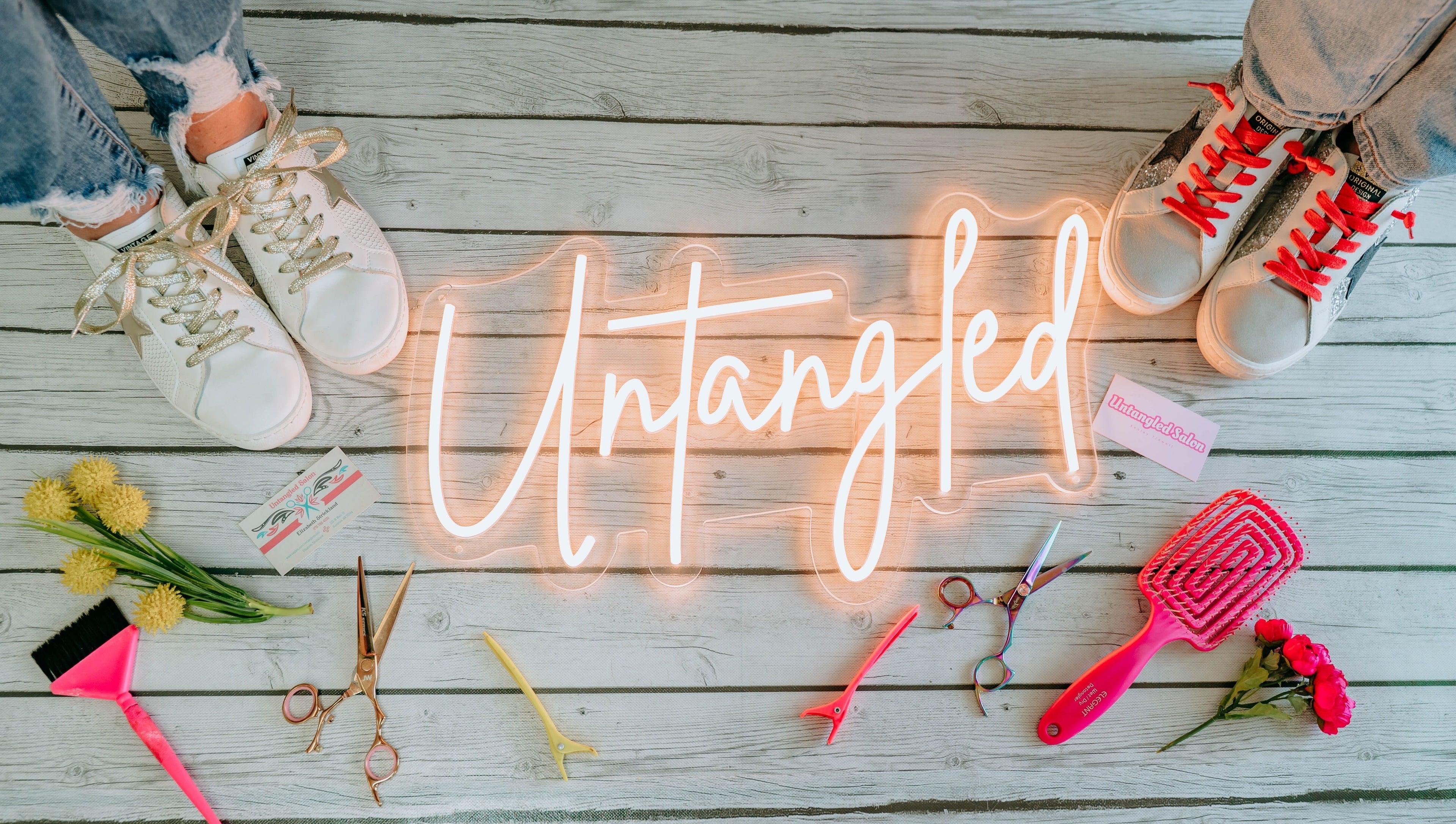 "Untangled Salon" neon sign with tools and flowers on wooden floor in Hampton, Arkansas, US.