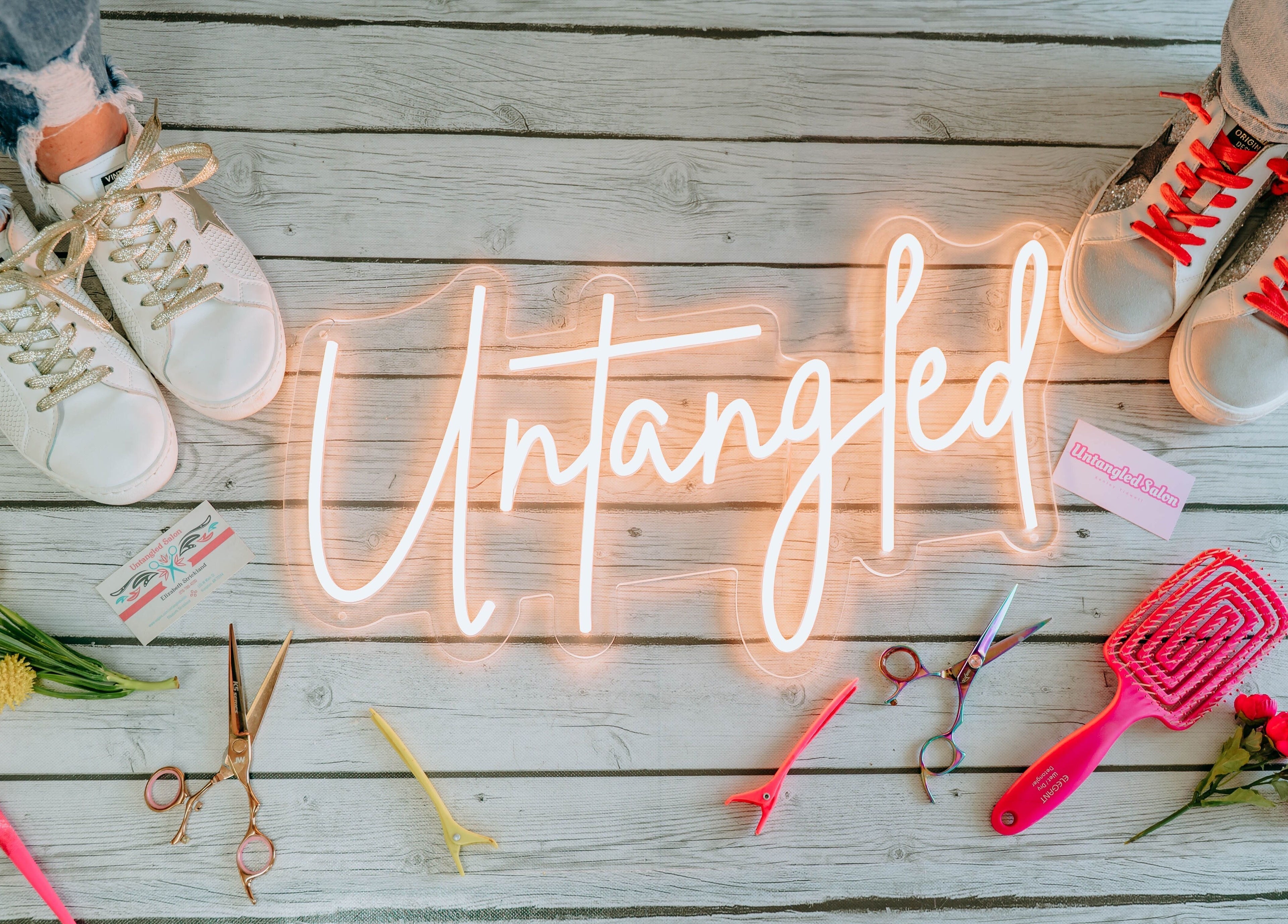 "Untangled Salon" neon sign with tools and flowers on wooden floor in Hampton, Arkansas, US.