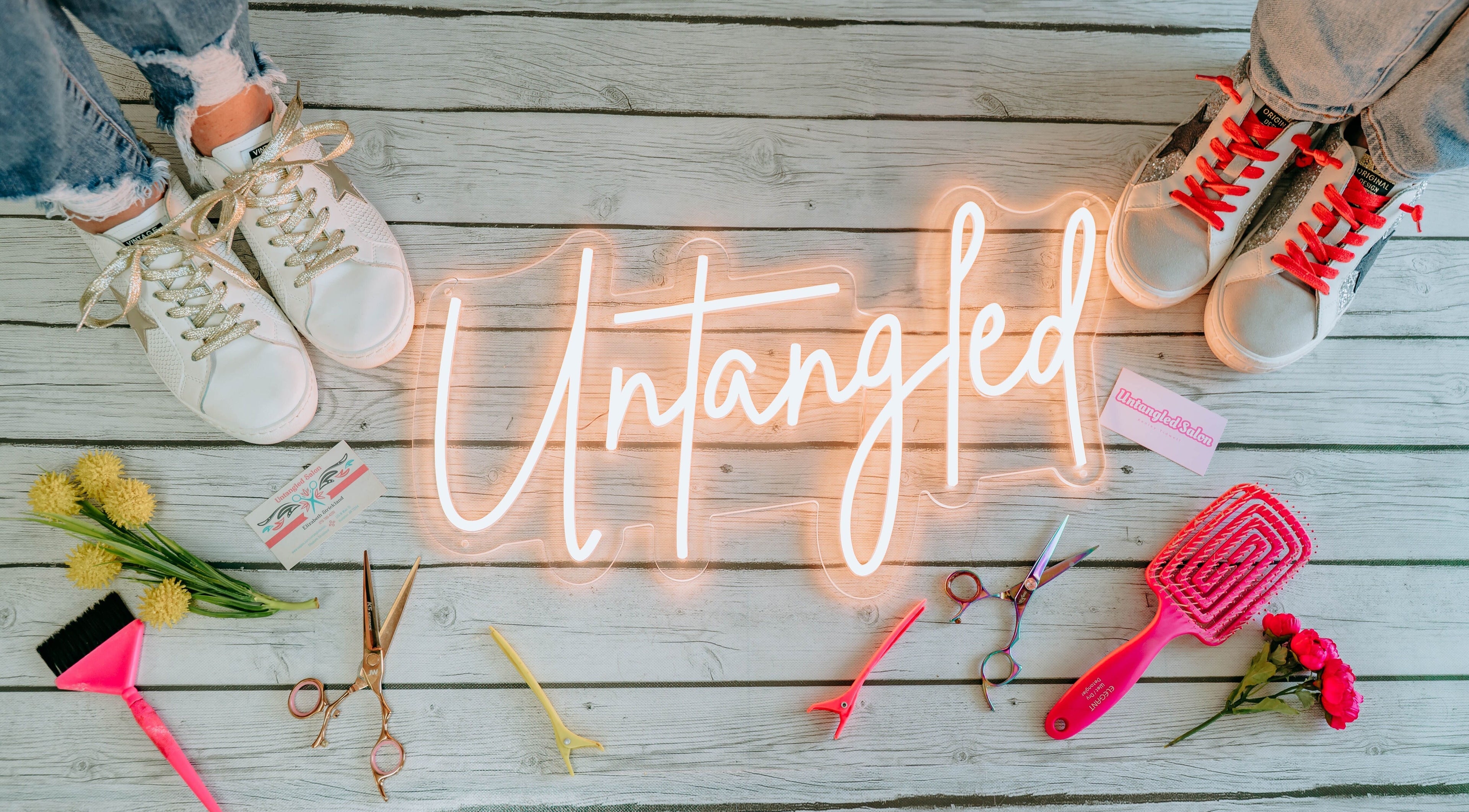 "Untangled Salon" neon sign with tools and flowers on wooden floor in Hampton, Arkansas, US.