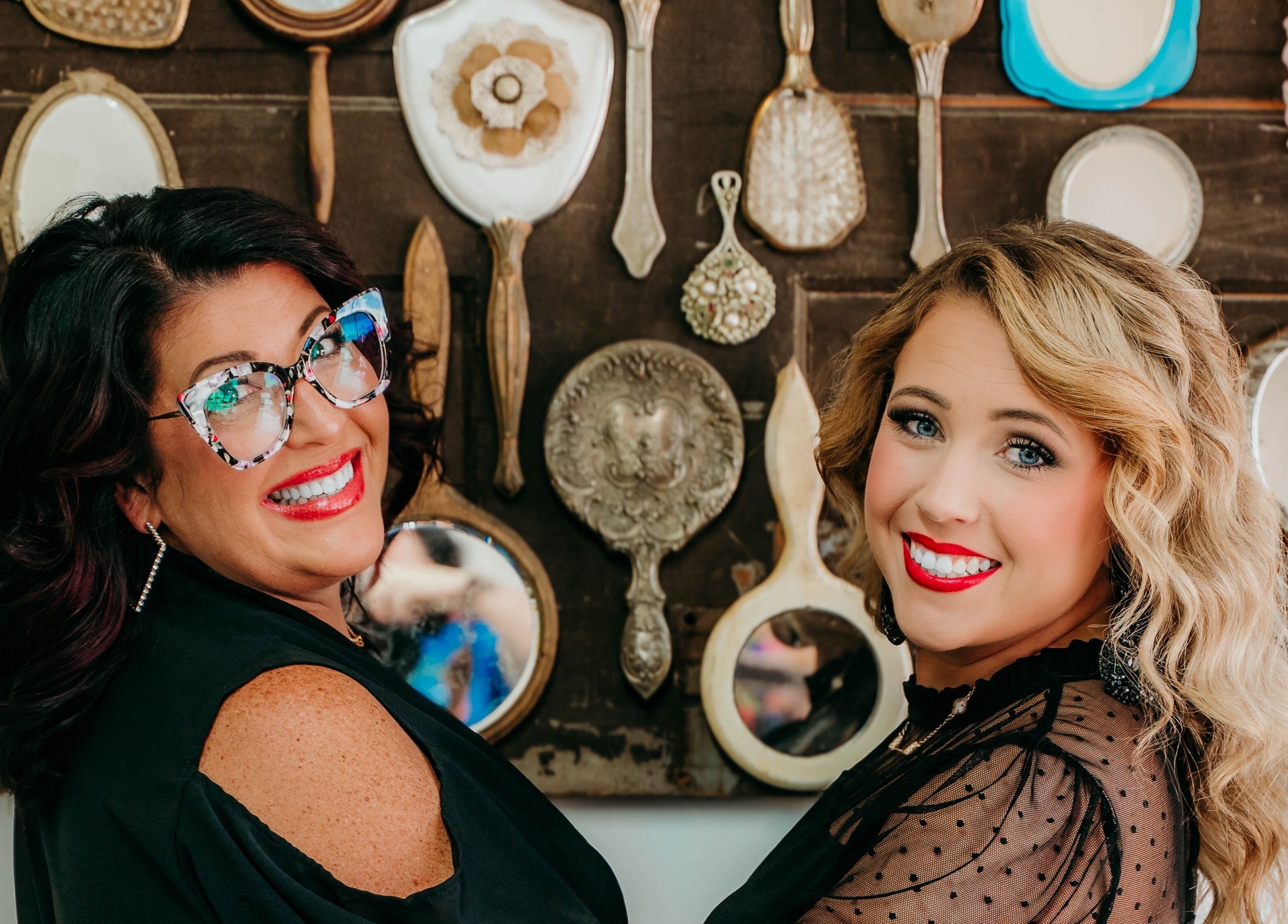 Stylish women smiling at Untangled Salon, Hampton, Arkansas, US with vintage mirrors in the background.