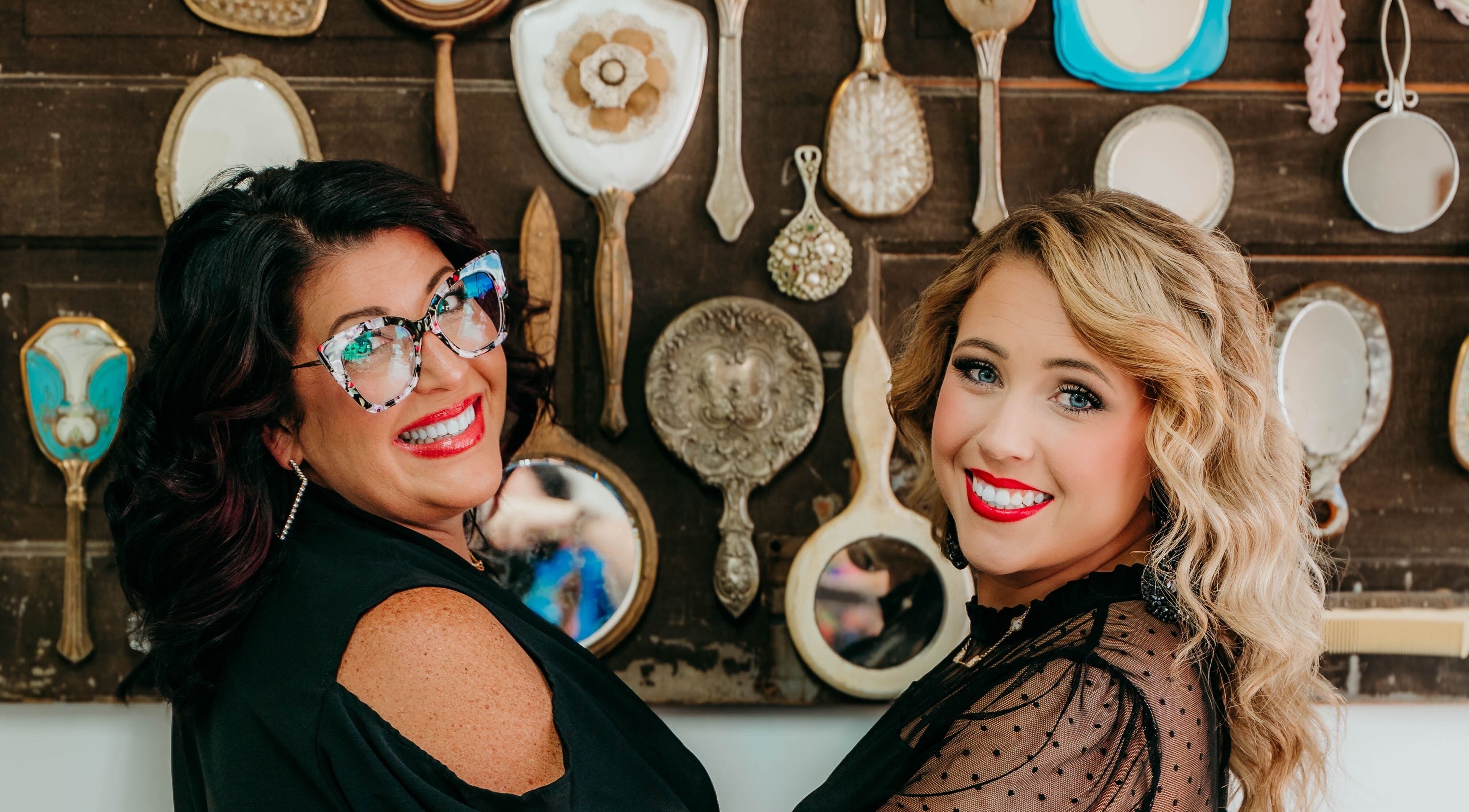 Stylish women smiling at Untangled Salon, Hampton, Arkansas, US with vintage mirrors in the background.