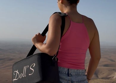 Vue éloignée de Doll's Beauty & Barber, Marrakech-safi, avec un sac arborant le logo, surplombant le désert.