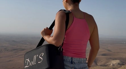 Vue éloignée de Doll's Beauty & Barber, Marrakech-safi, avec un sac arborant le logo, surplombant le désert.