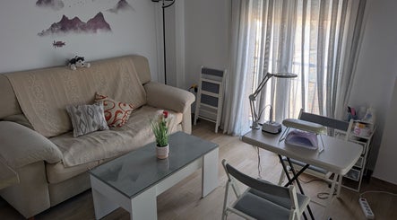 Zona acogedora en Bren Estetica, Brenes, Andalucía, ES, con sofá, mesa y herramientas de belleza.