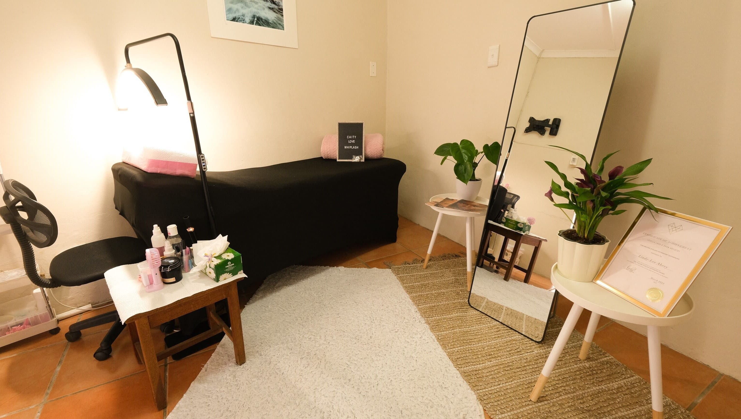 Cozy treatment room at Whiplash, East London, Eastern Cape, ZA, with a massage table, mirror, and plants.