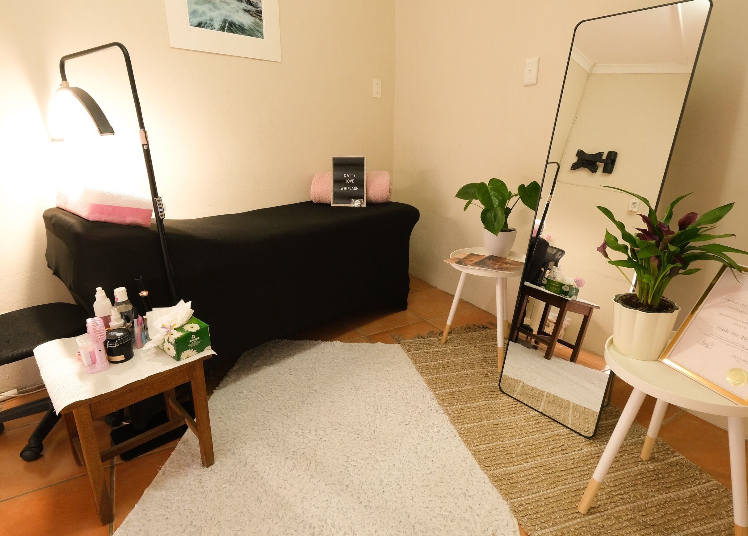 Cozy treatment room at Whiplash, East London, Eastern Cape, ZA, with a massage table, mirror, and plants.