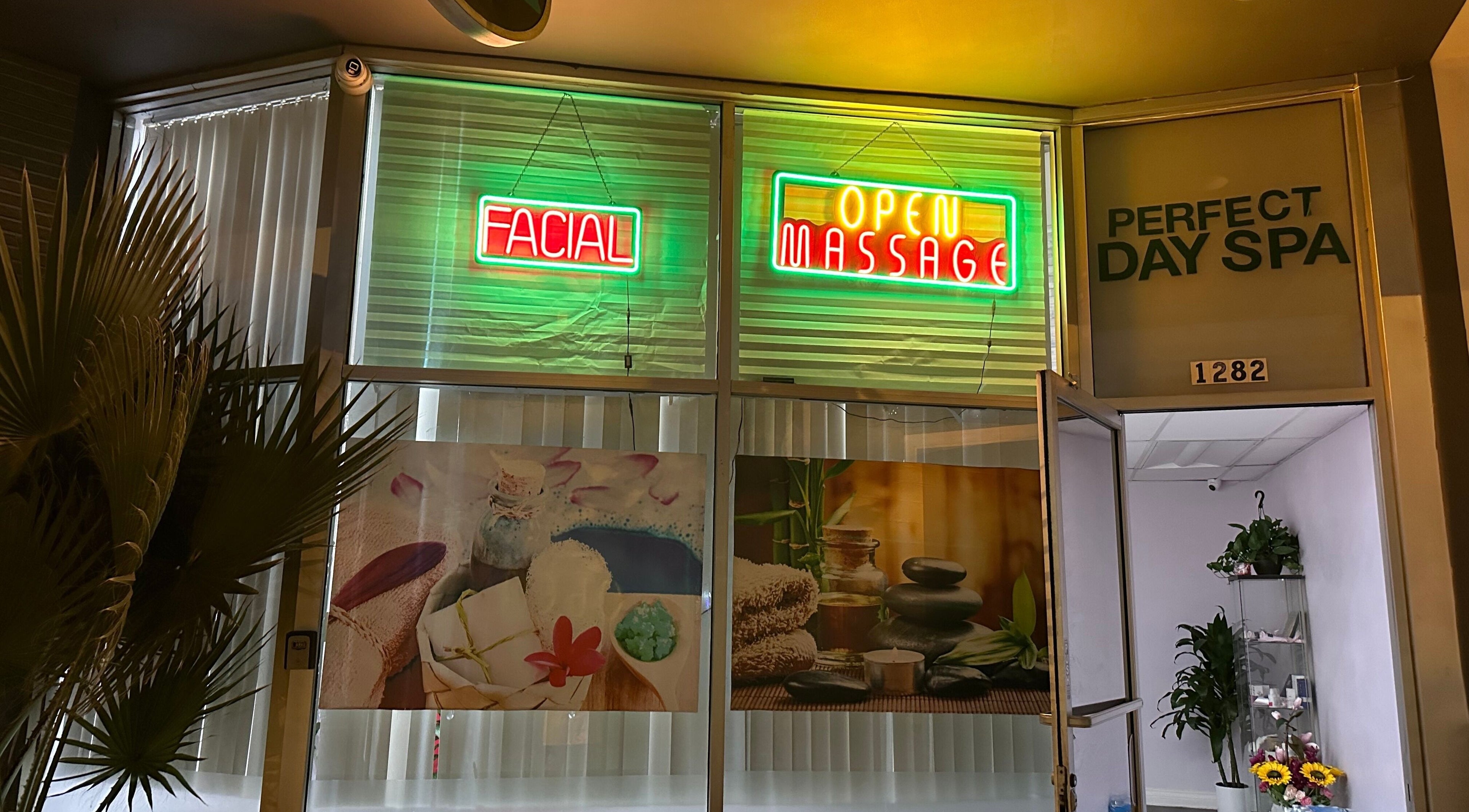 Entrance of Perfect Day SPA in Pasadena, California, US with bright neon signs for facials and massages.