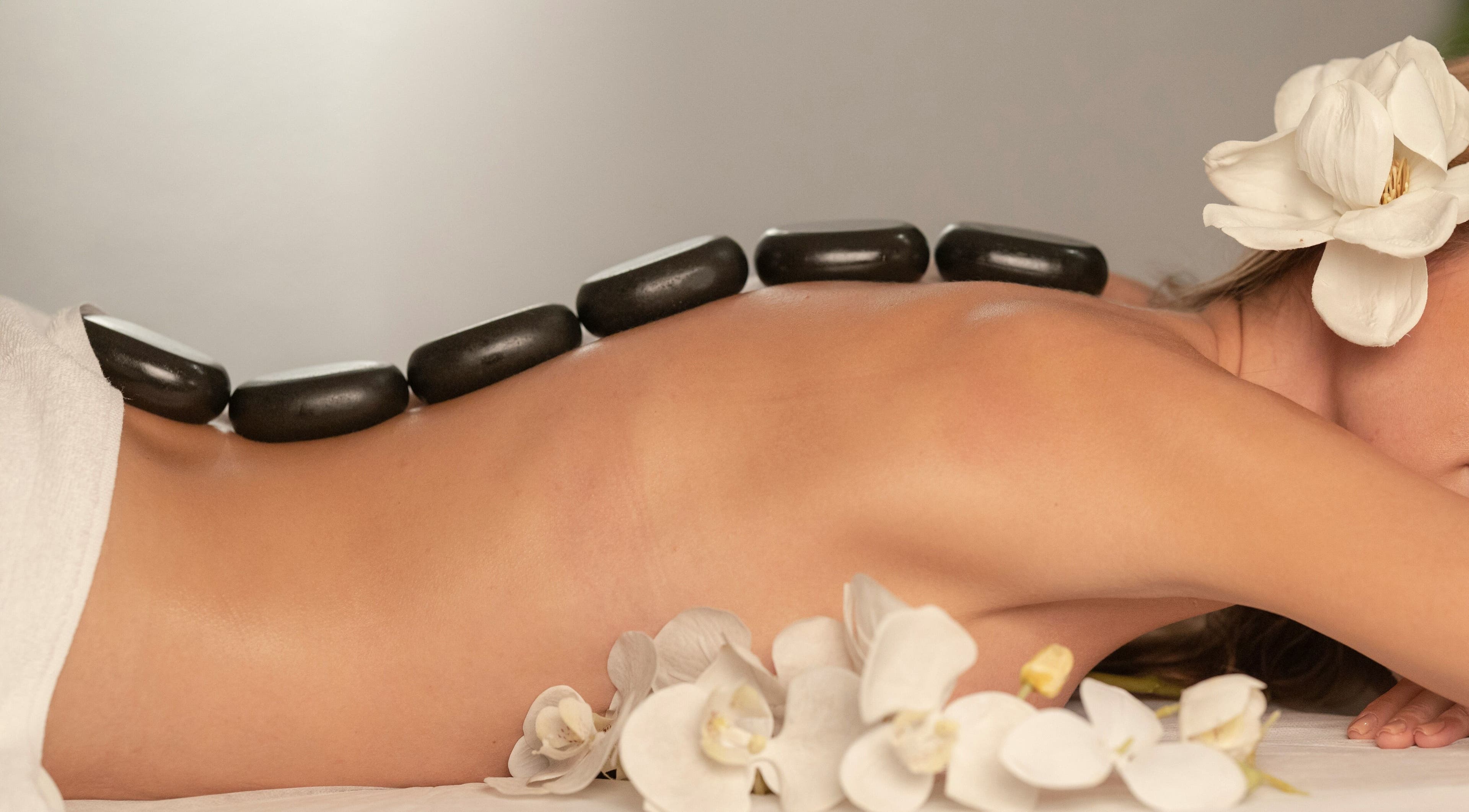 Relaxing hot stone massage at Perfect Day SPA, Pasadena, California, US with orchids for a serene experience.