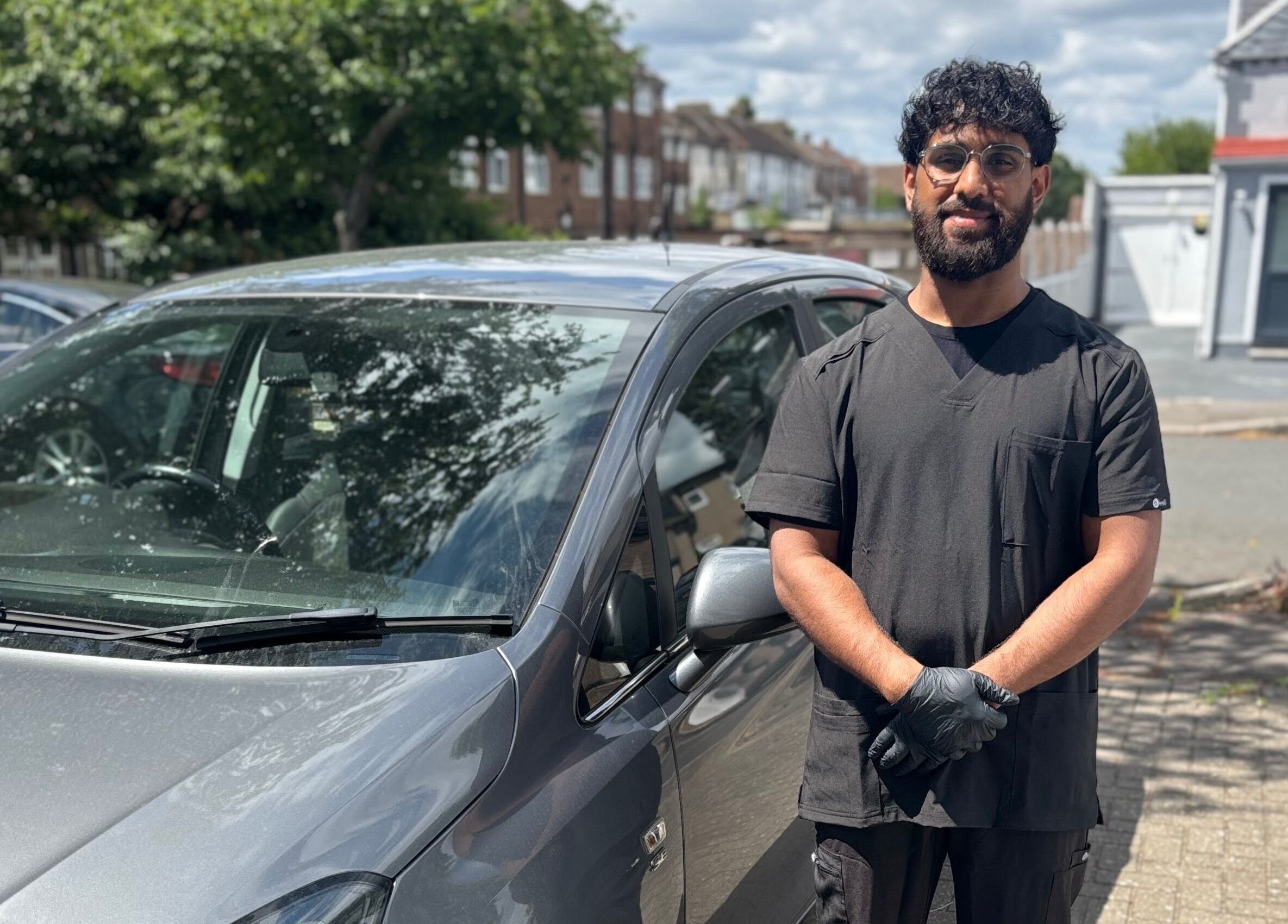 Professional at JSB Practices in Ilford, England, GB, standing by a car.