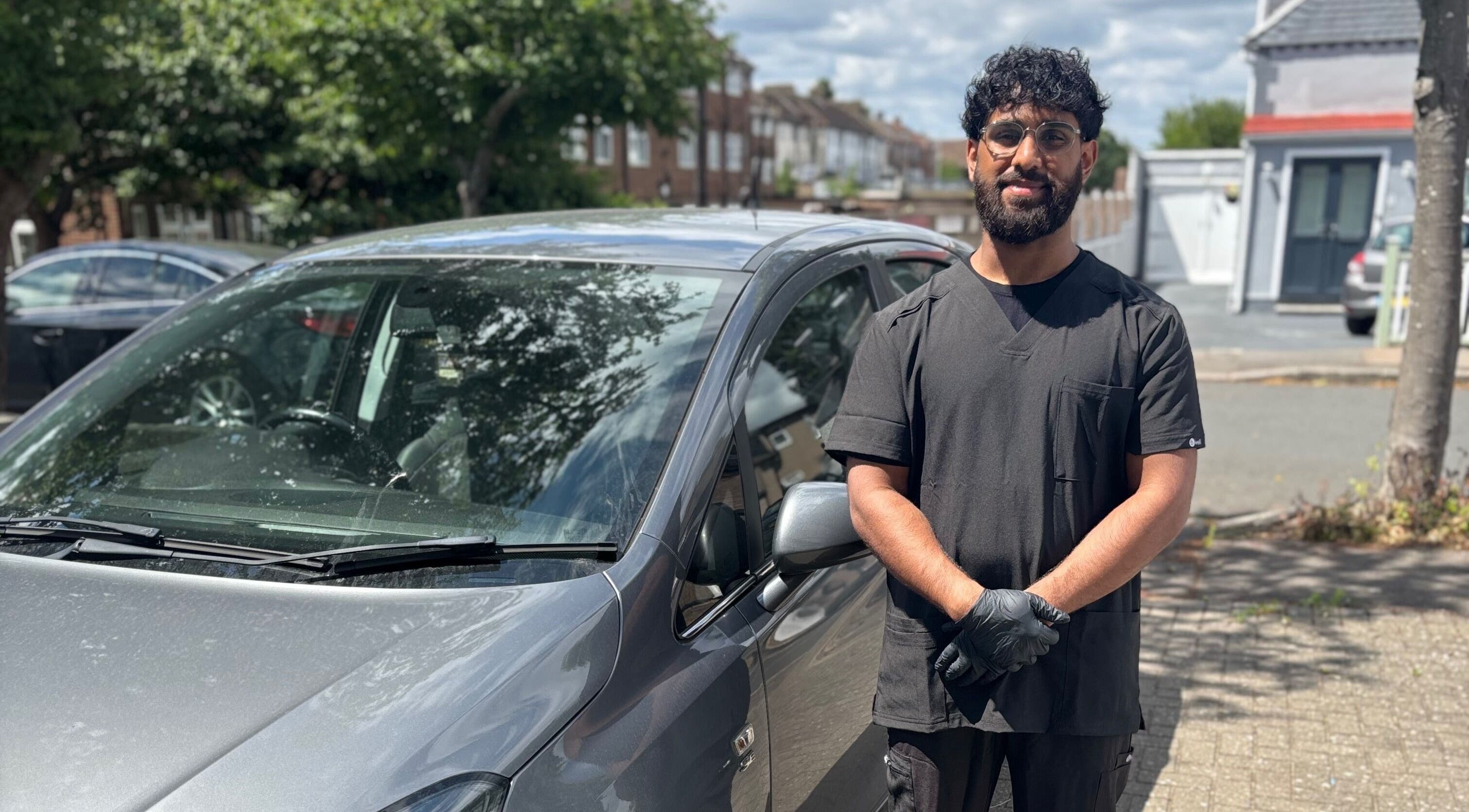 Professional at JSB Practices in Ilford, England, GB, standing by a car.