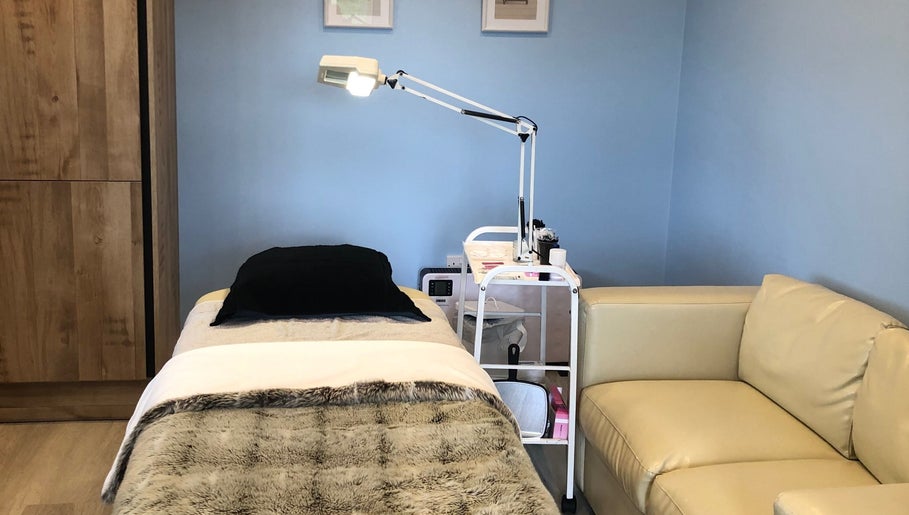 A serene treatment room at Beauty by Appointment, Colgate, England, GB with a massage table and cozy seating.