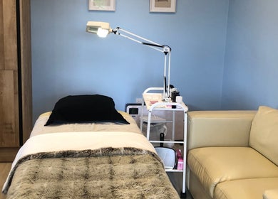 A serene treatment room at Beauty by Appointment, Colgate, England, GB with a massage table and cozy seating.