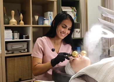 Tratamiento facial en Solabella, Orlando, Florida, US, con profesional usando rodillos dorados.
