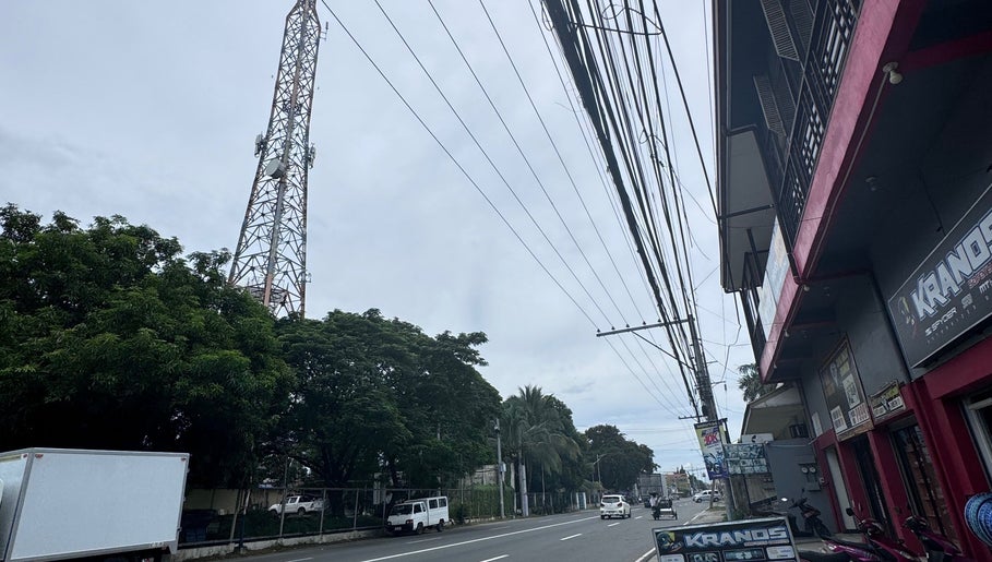 Street view near ROYAL GEM SALON CAPAS BRANCH, Capas, Central Luzon, PH, showcasing trees and a telecommunications tower.