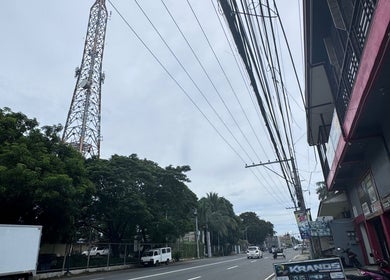 Street view near ROYAL GEM SALON CAPAS BRANCH, Capas, Central Luzon, PH, showcasing trees and a telecommunications tower.