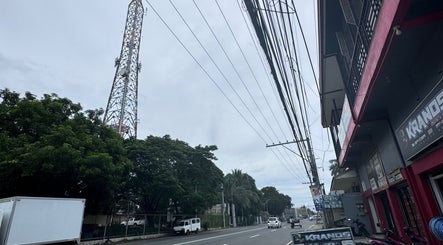 Street view near ROYAL GEM SALON CAPAS BRANCH, Capas, Central Luzon, PH, showcasing trees and a telecommunications tower.