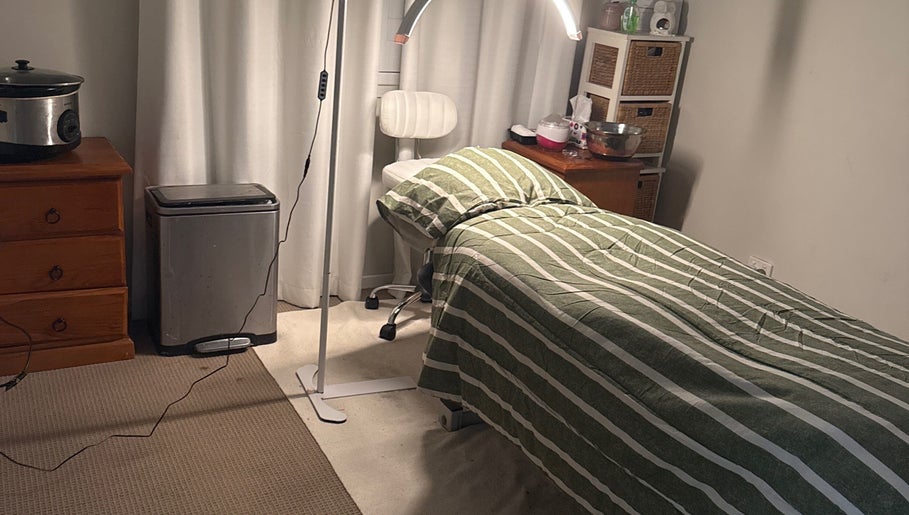 Cozy treatment room at Elegance by Bronte, Uralla, New South Wales, AU, featuring a striped bed and relaxing ambiance.