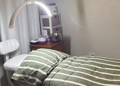 Calm treatment room at Elegance by Bronte, Uralla, New South Wales, AU with striped bedding and cozy lighting.
