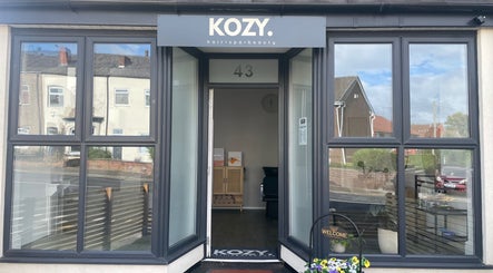 Entrance of KOZY. beauty venue in Hindley, England, GB with large windows and welcoming decor.