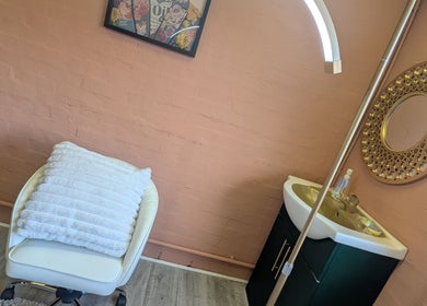 Elegant corner at NailedItByLarna, Redditch, England, GB with plush chair and decorative mirror.