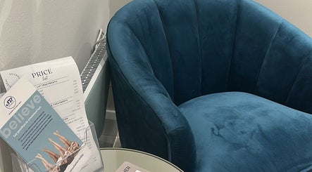 A plush blue chair beside brochures and price lists at The Clinic by Jessica May, Lowton, England, GB.