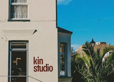 Front view of Kin Studio in Margate, England, showcasing palm trees and a clear blue sky.