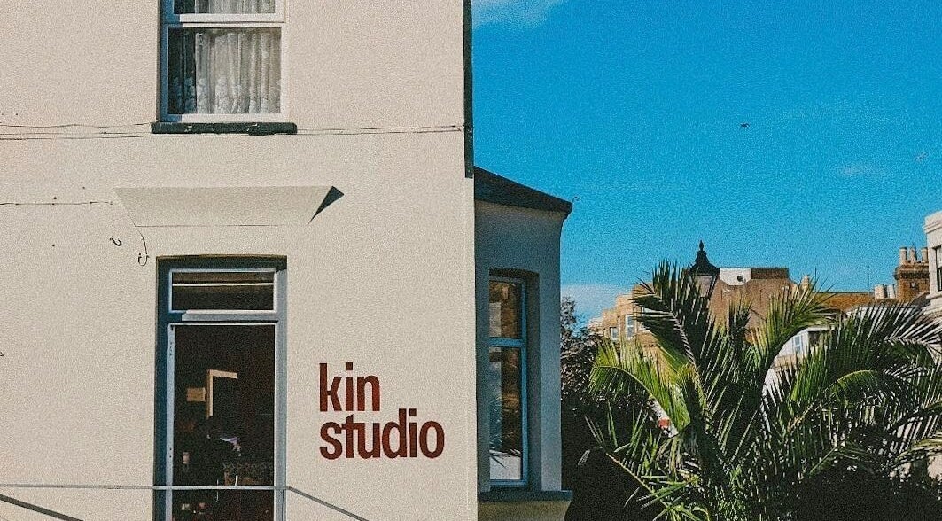 Front view of Kin Studio in Margate, England, showcasing palm trees and a clear blue sky.