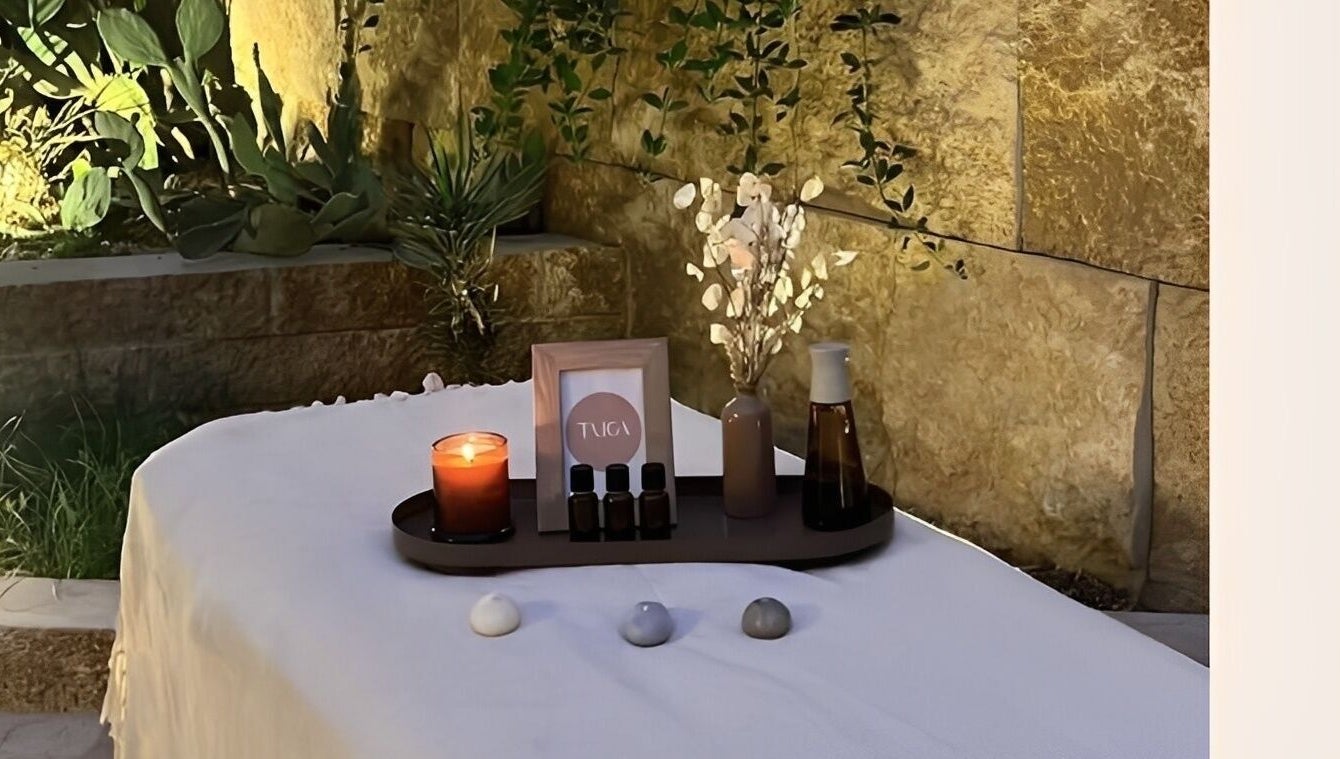 طاولة تدليك في Taiga Spa في الرياض، منطقة الرياض، SA، مزينة بشموع ومواد طبيعية.