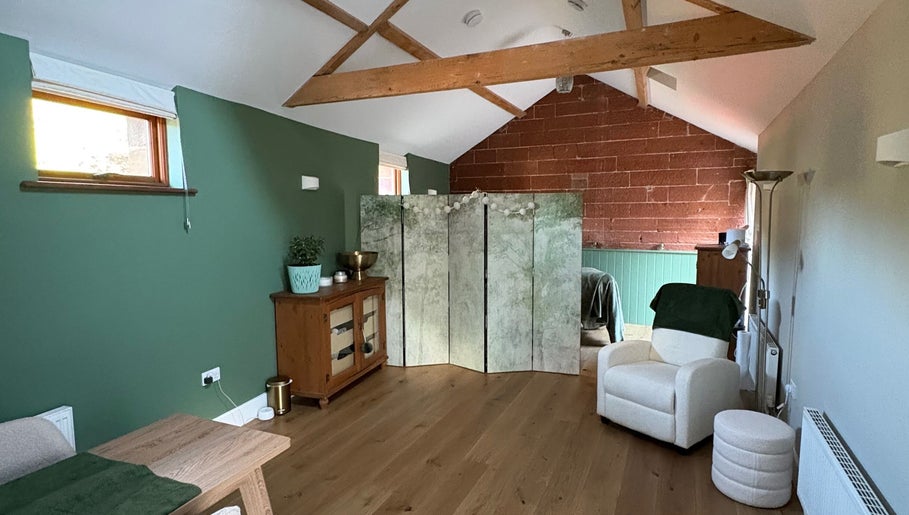 Relaxing wellness space at Feathers Health & Beauty in Dalston, England, GB with green walls and cozy seating.