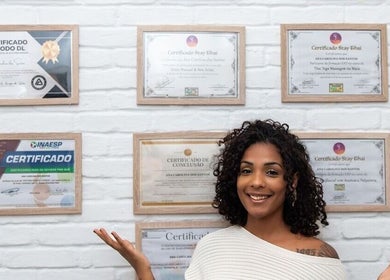 Profissional sorrindo com certificados na parede em Xantos Massagem, São Paulo, São Paulo, BR.