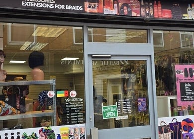 Exterior view of Arty beauty store in Rochdale, England, showcasing wigs and accessories in window.
