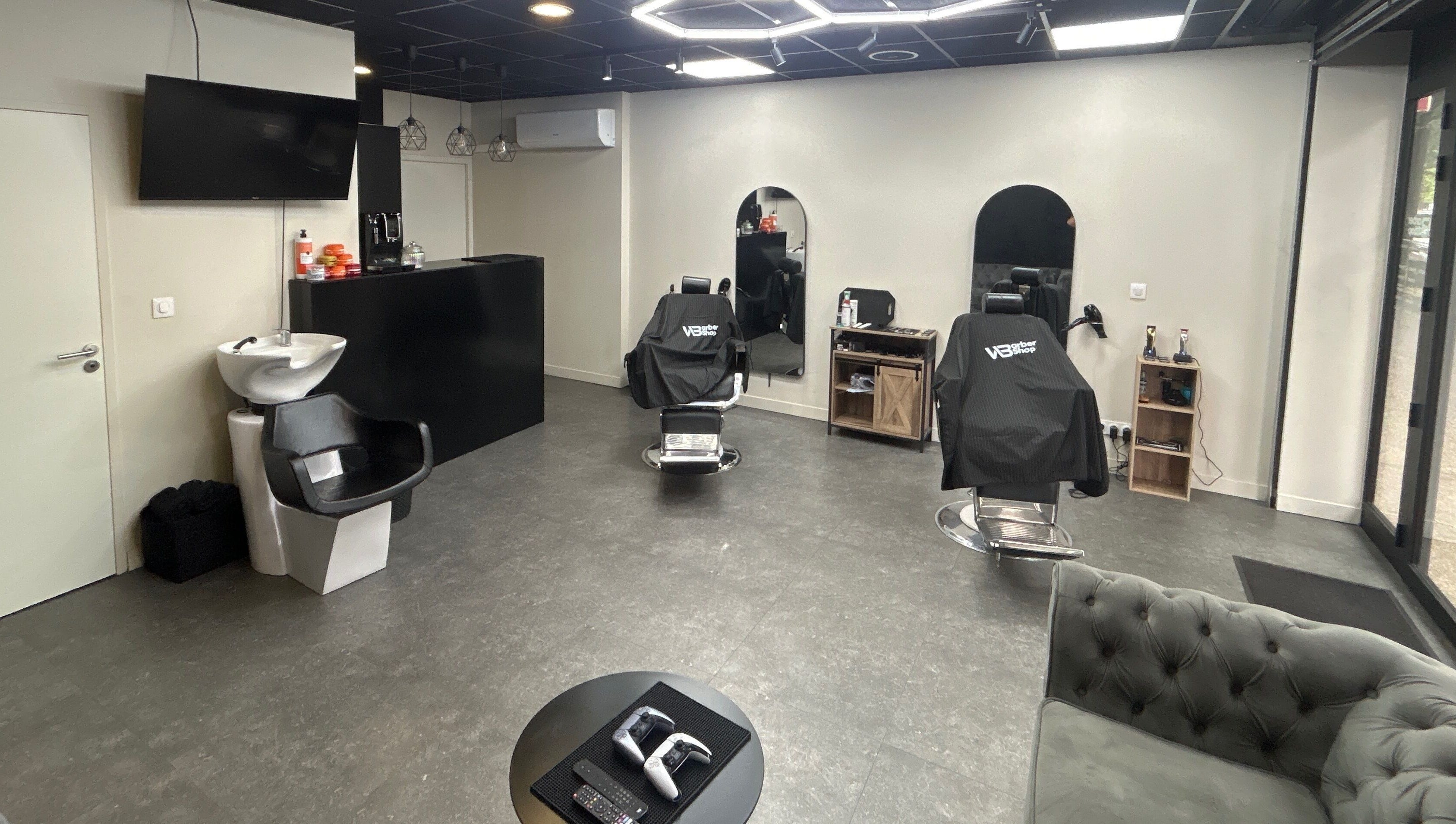 Intérieur moderne de Wbarbershop à Échirolles, Auvergne-rhône-alpes, FR avec fauteuils de coiffure noirs.